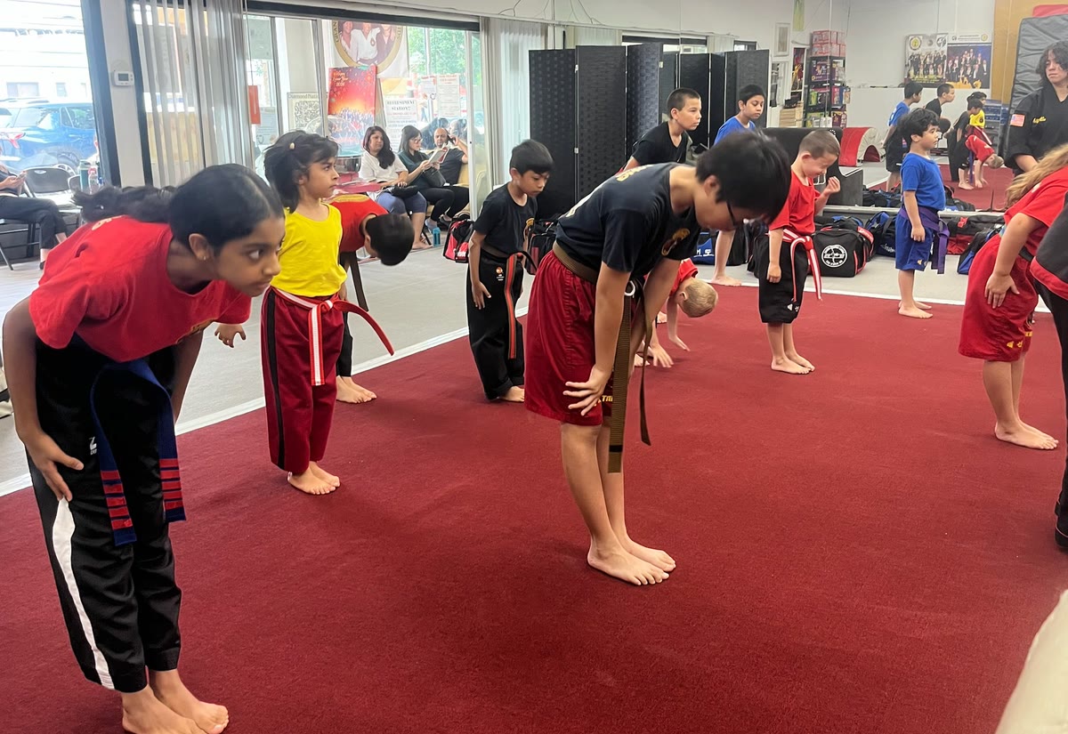 Students in colored belts bow together at the start of class.
